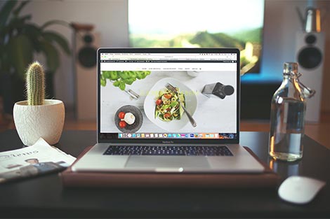 Blick auf einen Laptot - am Bildschirm sieht man eine Website mit einem Teller inklusive Gericht.